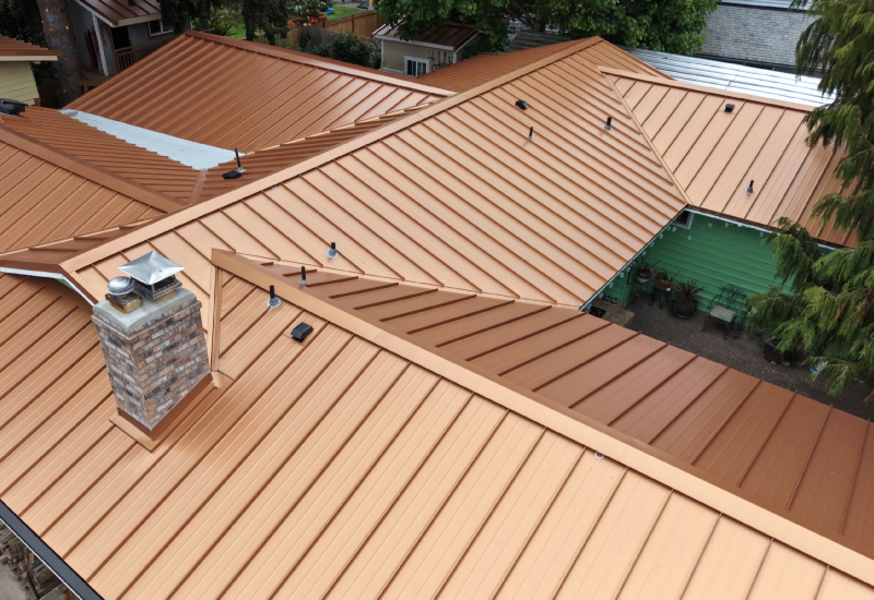 Aerial view of the completed Copper Penny standing seam metal roof showing multiple rooflines, valleys, and chimney flashing