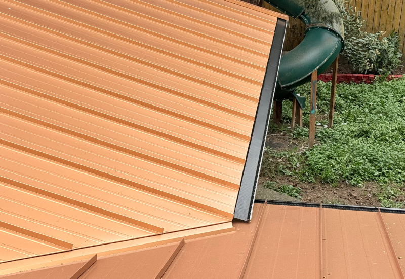 Close-up of metal roofing with black perforated gutter guards installed along the roof edges
