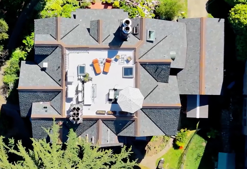 Overhead aerial view showing the historic home's complex rooflines, copper detailing, and rooftop terrace