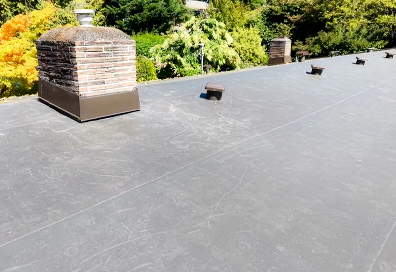 Close-up showing the TPO roofing membrane, seams, and chimney flashing
