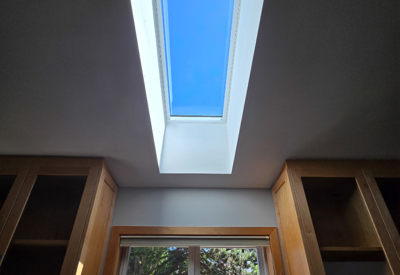 Interior view of a VELUX skylight installed above the kitchen window, bringing more natural daylight into the kitchen workspace.