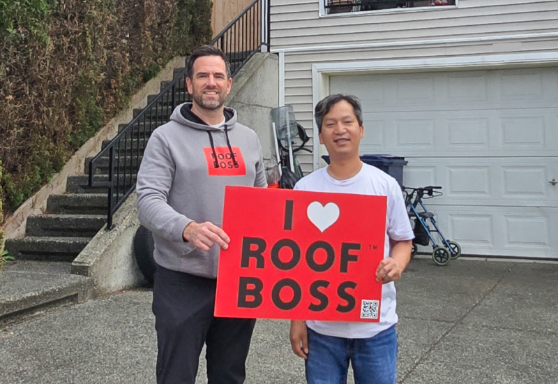 ROOF BOSS customer with estimator holding an 'I Love ROOF BOSS' sign after completion of the roofing project