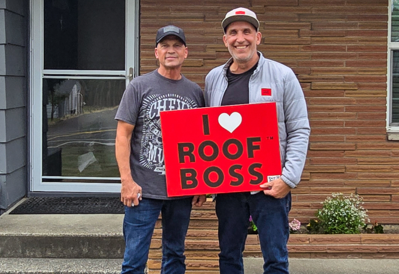 ROOF BOSS customer with estimator holding an 'I Love ROOF BOSS' sign after completion of the roofing project