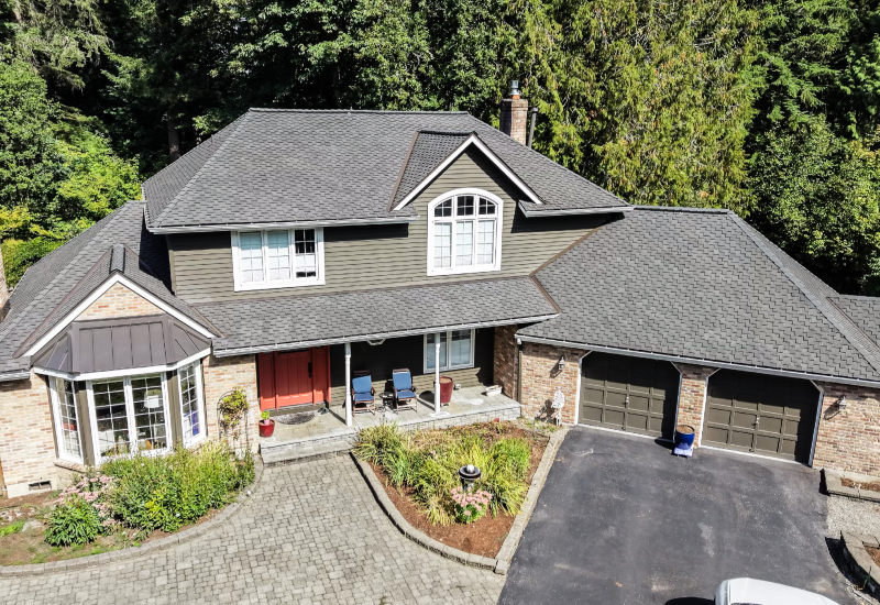 Owens Corning Woodmoor roof in Mesquite with standing seam metal accents in Dark Bronze over the bay window