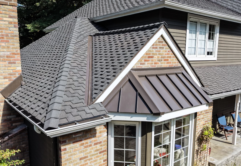 Standing seam metal accent roof over the bay window alongside Woodmoor shingles