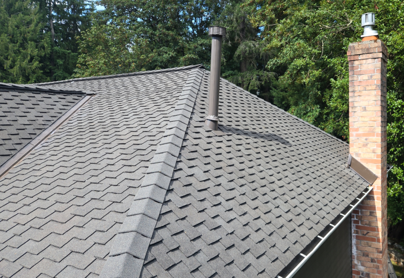 Close-up showing the dimensional profile, chimney flashing, and ridge caps of Woodmoor shingles