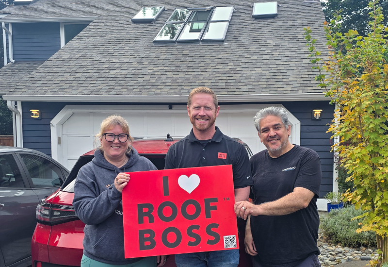 ROOF BOSS/Seattle Skylights customers with estimator holding an 'I Love ROOF BOSS' sign after completion of the skylight project